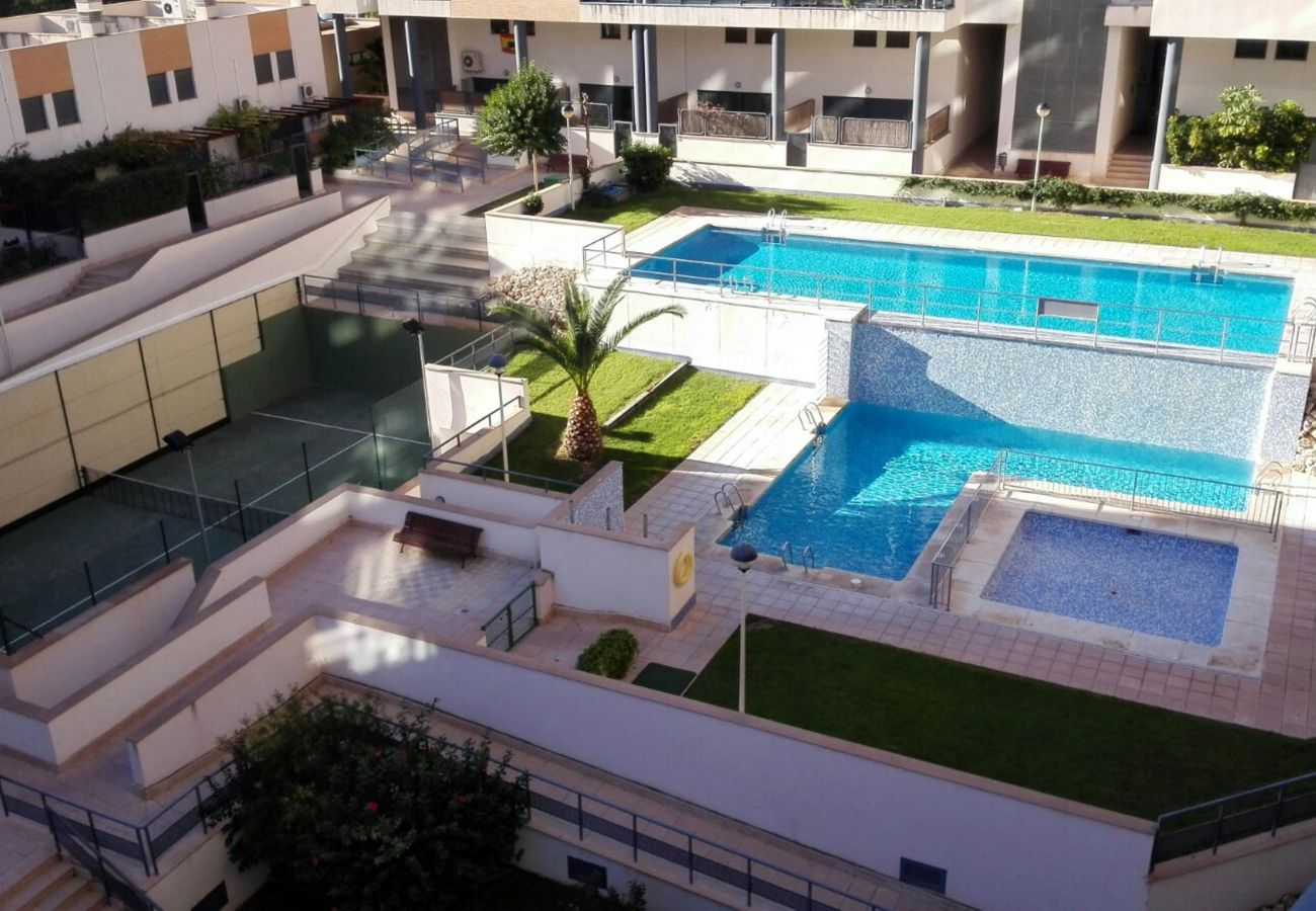 Zonas comunes del apartamento vacacional, pista de tenis, piscina y césped natural