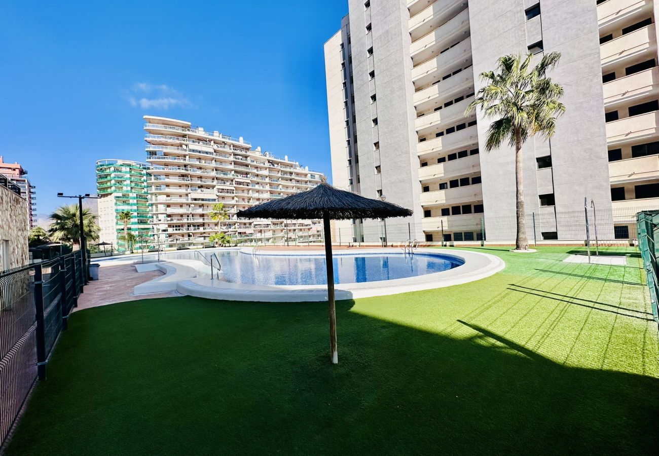 Zona común de un apartamento vacacional en Alicante, con piscina y césped natural