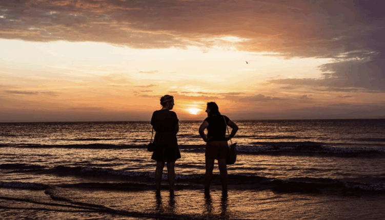 dos chicas viendo el atardecer en la playa